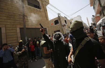 A Palestinian militant fires a weapon in the air during the funeral of Palestinian Mohammed Abu Latifa, 19, in Qalandiya refugee camp, near the West Bank city of Ramallah July 27, 2015. Abu Latifa, wanted on suspicion of planning a militant attack, fell to his death from a rooftop on Monday as he fled from police in the occupied West Bank, Israeli police said, an account disputed by a witness. REUTERS/Mohamad Torokman
