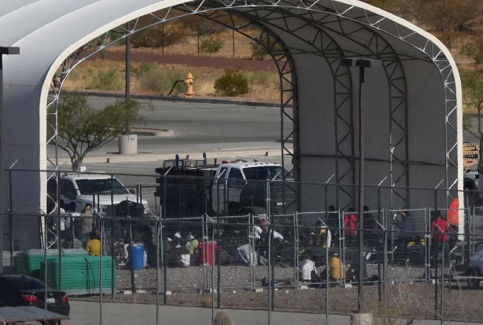 People are seen congregated in an outdoor shelter outside of the Ajo Border Patrol Station.