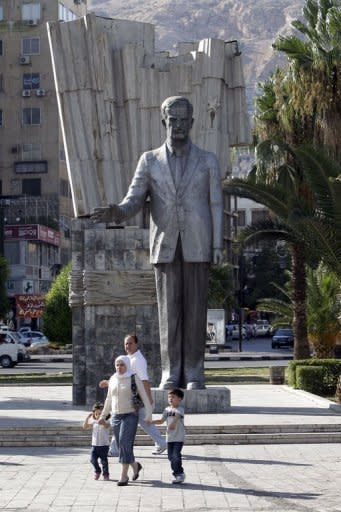 People walk past a statue of the late Syrian president Hafez al-Assad, father of current president Bashar, in a public garden in central Damascus