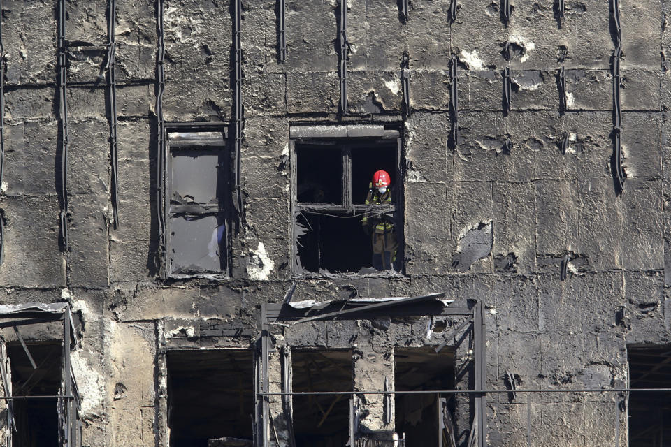 Firefighters work inside a burned block building in Valencia, Spain, Friday, Feb. 23, 2024. As firefighters and scientific police began inspecting the interior of two residential towers that were destroyed by fire in the eastern Spanish city of Valencia, killing four people, questions abounded as to how the fire spread so rapidly. Authorities said 14 people were still missing following the blaze at the modern complex Thursday. (AP Photo/Alberto Saiz)