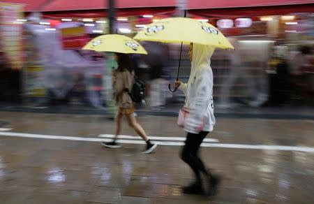 Shoppers walk under umbrellas as Typhoon Lan approaches Japan's mainland, in Osaka, western Japan, October 22, 2017. REUTERS/Thomas White