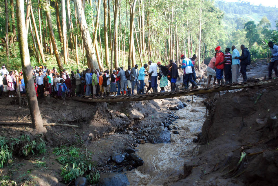 Residence cross a river filled with mud in Bududa District, Uganda, Friday, Oct. 12, 2018. At least 30 people died in mudslides triggered by torrential rains in a mountainous area of eastern Uganda that is prone to such disasters, a Red Cross official said Friday. More victims were likely to be discovered when rescue teams access all the affected areas in the foothills of Mount Elgon, said Red Cross spokeswoman Irene Nakasiita. (AP Photo/ Ronald Kabuubi)