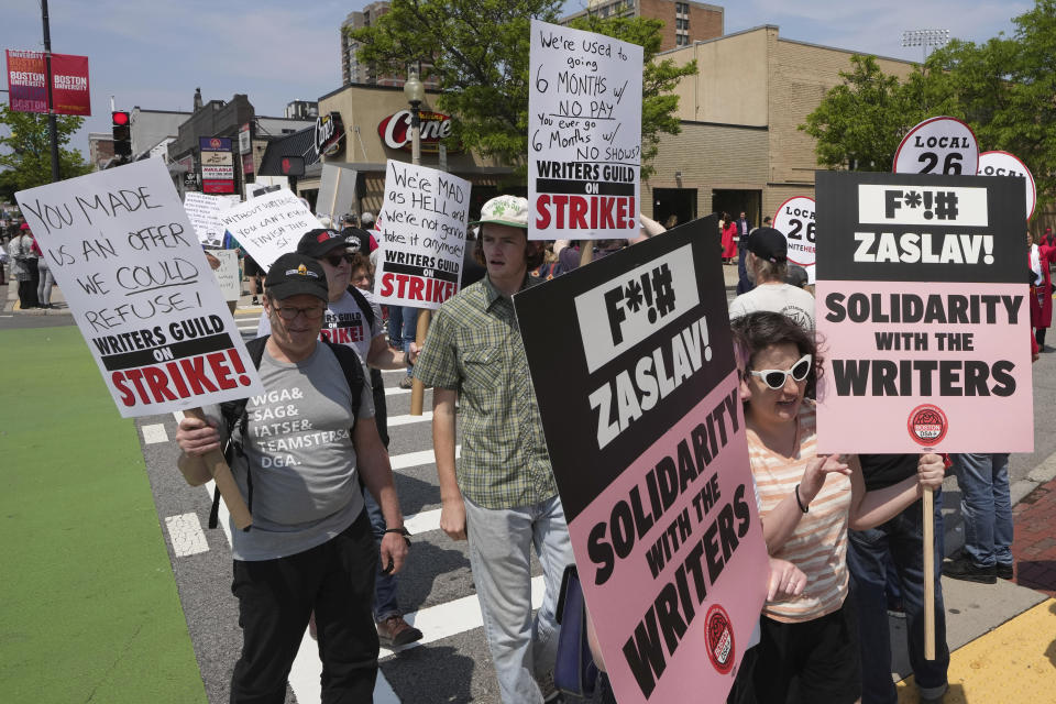 Protesters supporting the Hollywood writers' strike march in a picket line outside an entrance to Boston University commencement ceremonies, Sunday, May 21, 2023, in Boston. David Zaslav, president and CEO of Warner Bros. Discovery, delivered an address during ceremonies Sunday. (AP Photo/Steven Senne)