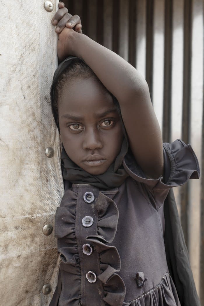 Naba Akbar Azien, an 8-year-old Sudanese girl whose family fled to neighboring Chad, poses in front of a building in Aboutengue. Her father, Aboubakar, sustained injuries back in his native Sudan that have complicated the already difficult task of adapting to life as a refugee.<span class="copyright">Nicolò Filippo Rosso</span>