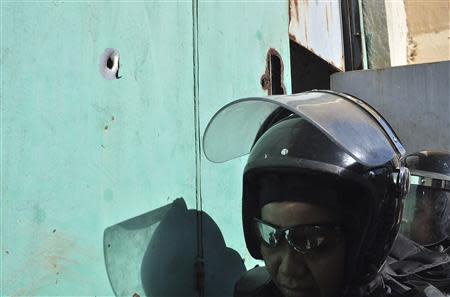 Riot policemen stand next to a bullet hole on a door after a gunfight in the Tuxpan prison in Iguala, in the Mexican State of Guerrero January 3, 2014. REUTERS/Jesus Solano