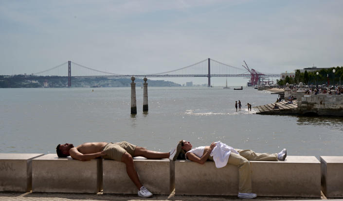 A couple sunbathes as tourists are seen in the background in Cais das Colunas in Lisbon, Portugal on May 19, 2022.<span class="copyright">Horacio Villalobos—Corbis/Getty Images</span>