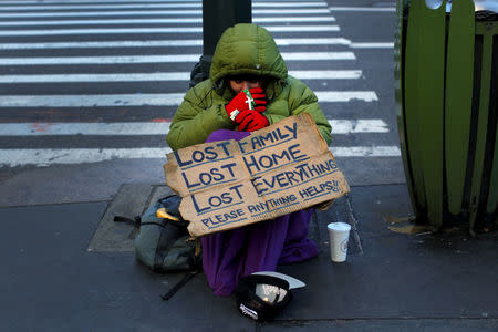 FILE PHOTO - A homeless woman sits bundled against the cold as she begs for handouts on East 42nd Street in the Manhattan borough of New York City, U.S. on January 4, 2016. REUTERS/Mike Segar/File Photo