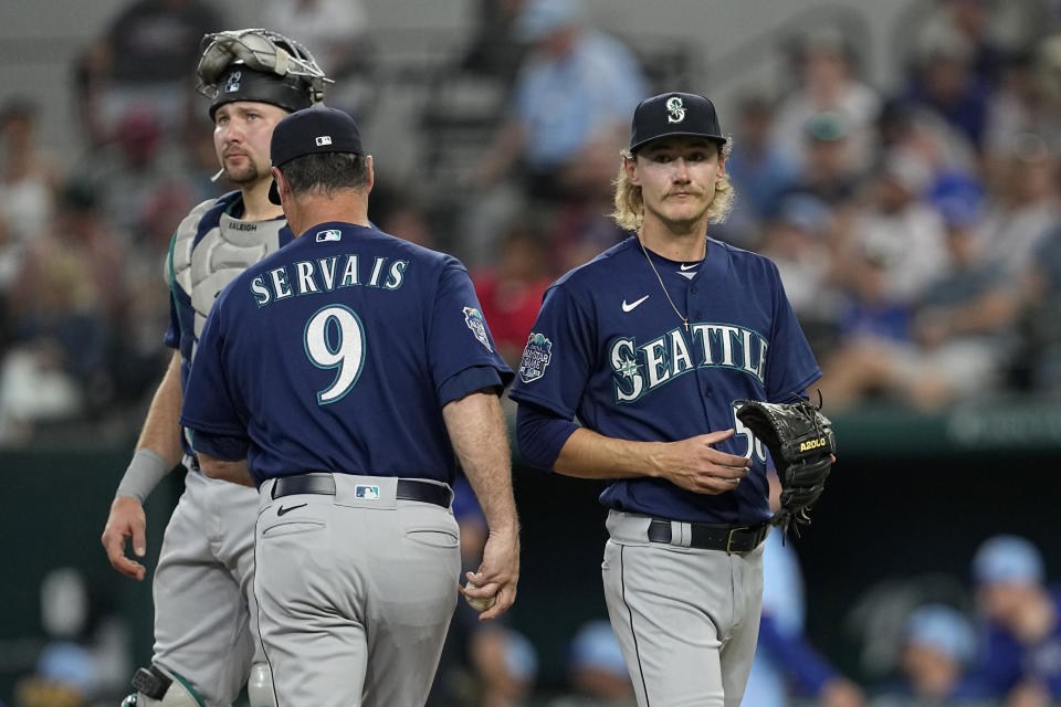 Seattle Mariners manager Scott Servais (9) takes the ball from starting pitcher Bryce Miller, right, as catcher Cal Raleigh, left, stands on the mound in the third inning of a baseball game against the Texas Rangers, Sunday, June 4, 2023, in Arlington, Texas. (AP Photo/Tony Gutierrez)