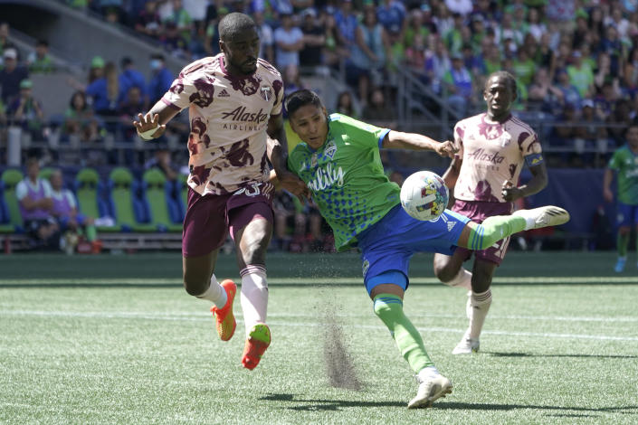 Seattle Sounders forward Raul Ruidiaz, center, takes aim on the ball as he is challenged by Portland Timbers defender Larrys Mabiala, left, during the second half of an MLS soccer match, Saturday, July 9, 2022, in Seattle. The Timbers won 3-0. (AP Photo/Ted S. Warren)