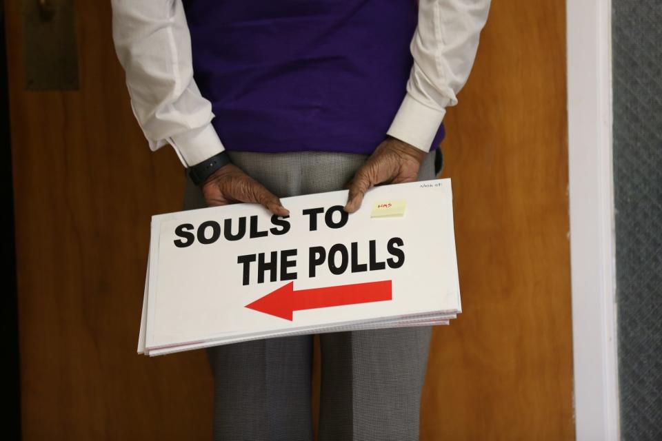 St. Joseph AME Church member holds signs that will show the way to an early voting site.