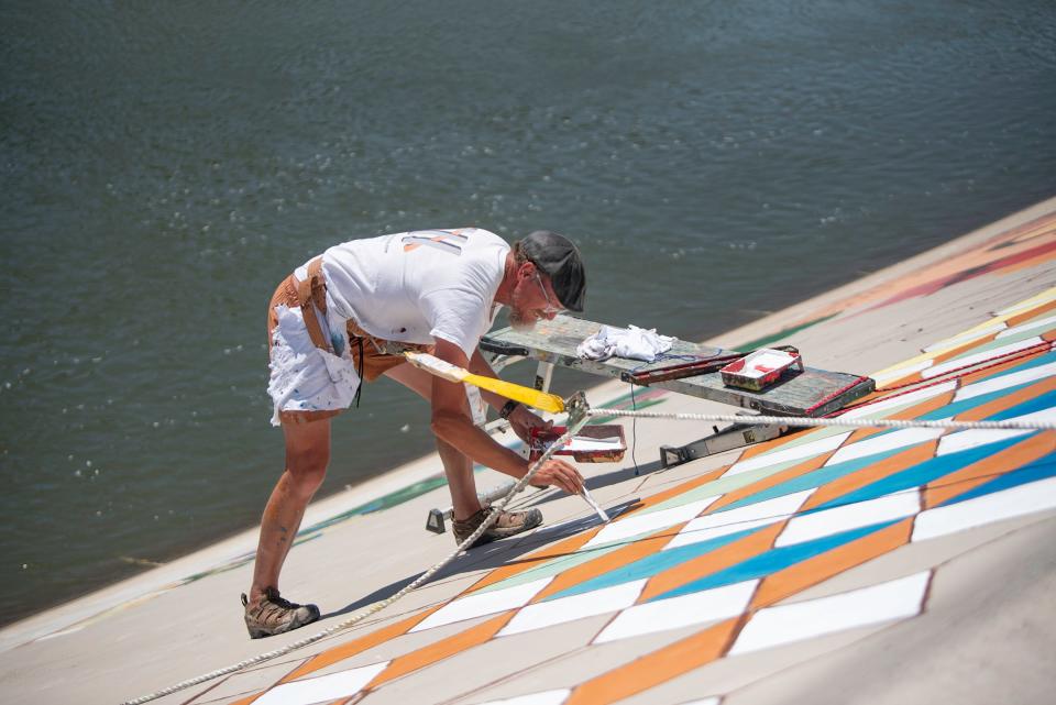 Artist Tim Nijenhuis paints a mural on the Arkansas River levee in Pueblo on Wednesday, August 9, 2023.