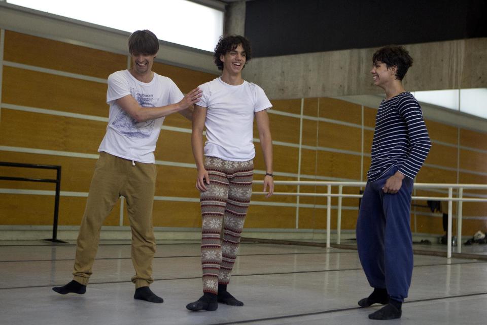 In this Aug. 15, 2012 photo, Isaac Hernandez, Mexico's most internationally acclaimed male ballet dancer, center, jokes with his younger brother Esteban Hernandez, right, and ballet master Uwe Fisher-Pettitt as they rehearse in Mexico City. Hernandez wants to change ballet in Mexico and aims to lead his countrymen to the practice barre in hopes they will grab on and get hooked, just as he did as a boy. (AP Photo/Dario Lopez-Mills)