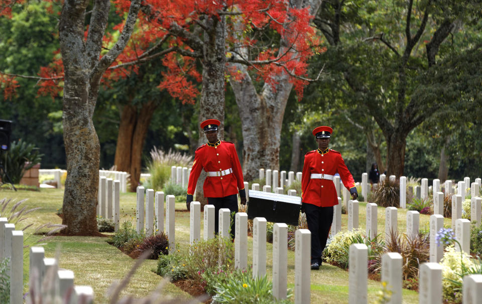 FILE - In this Sunday, Nov. 13, 2016 file photo, two members of Kenya's Military Police walk past graves as they leave after attending a Remembrance Sunday event, to honor the contribution of those British and Commonwealth military who died in the two World Wars and later conflicts, at the Nairobi War Cemetery in Kenya. The Commonwealth War Graves Commission has apologized after an investigation found that at least 161,000 mostly Africans and Indians who died fighting for the British Empire during World War I weren't properly honored due to "pervasive racism", according to findings released Thursday, April 22, 2021. (AP Photo/Ben Curtis, File)
