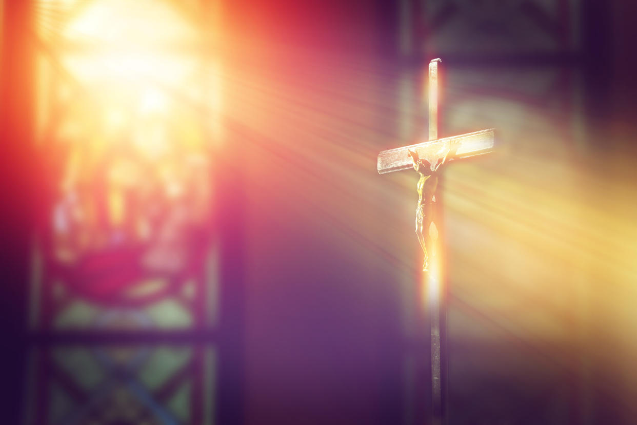 crucifix, jesus on the cross in church with ray of light from stained glass