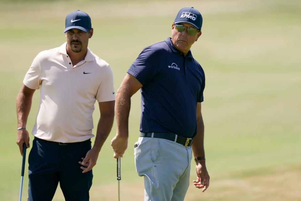 Brooks Koepka, left, and Phil Mickelson watch Mickelson's putt on the fourth green during the final round at the PGA Championship on the Ocean Course on May 23, 2021, in Kiawah Island, S.C.