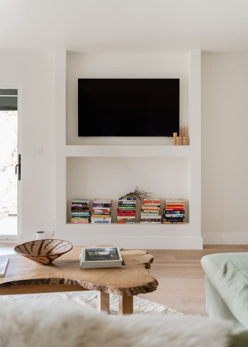 Neatly stacked books on bottom shelf with television above.