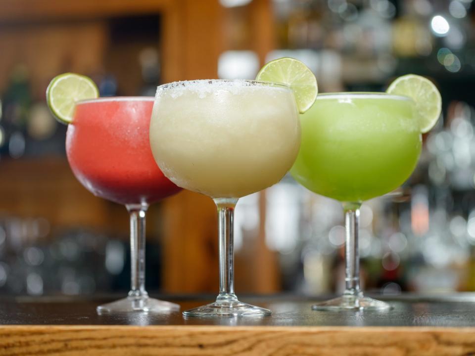 Ein Trio von gefrorenen Margaritas (rot, weiß und grün), die auf einer Bar aufgereiht sind