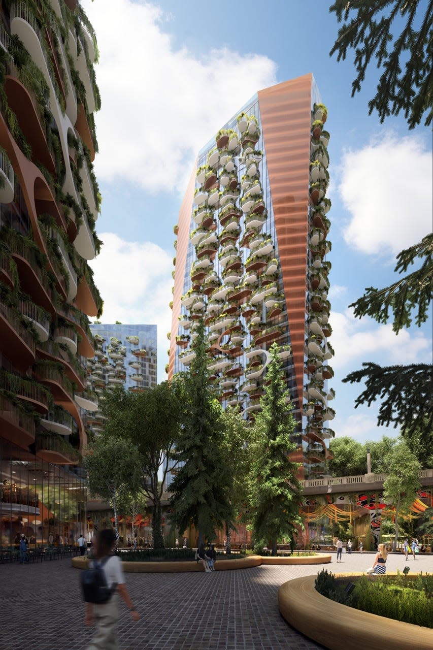 Close-up of a Sen̓áḵw development tower with hanging patios covered in green foliage 