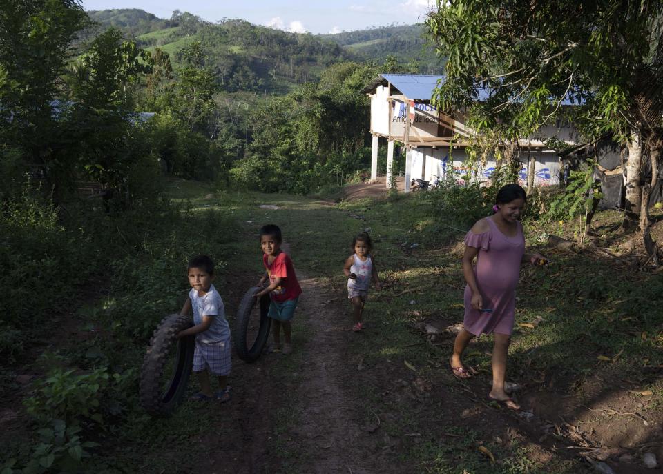 Children play with tires in the Chambira community, in the Peru Amzaon, Tuesday, Oct. 4, 2022. Residents in Kichwa Indigenous villages in Peru say they fell into poverty after the government turned their ancestral forest into a national park, restricted hunting and sold forest carbon credits to oil companies. (AP Photo/Martin Mejia)