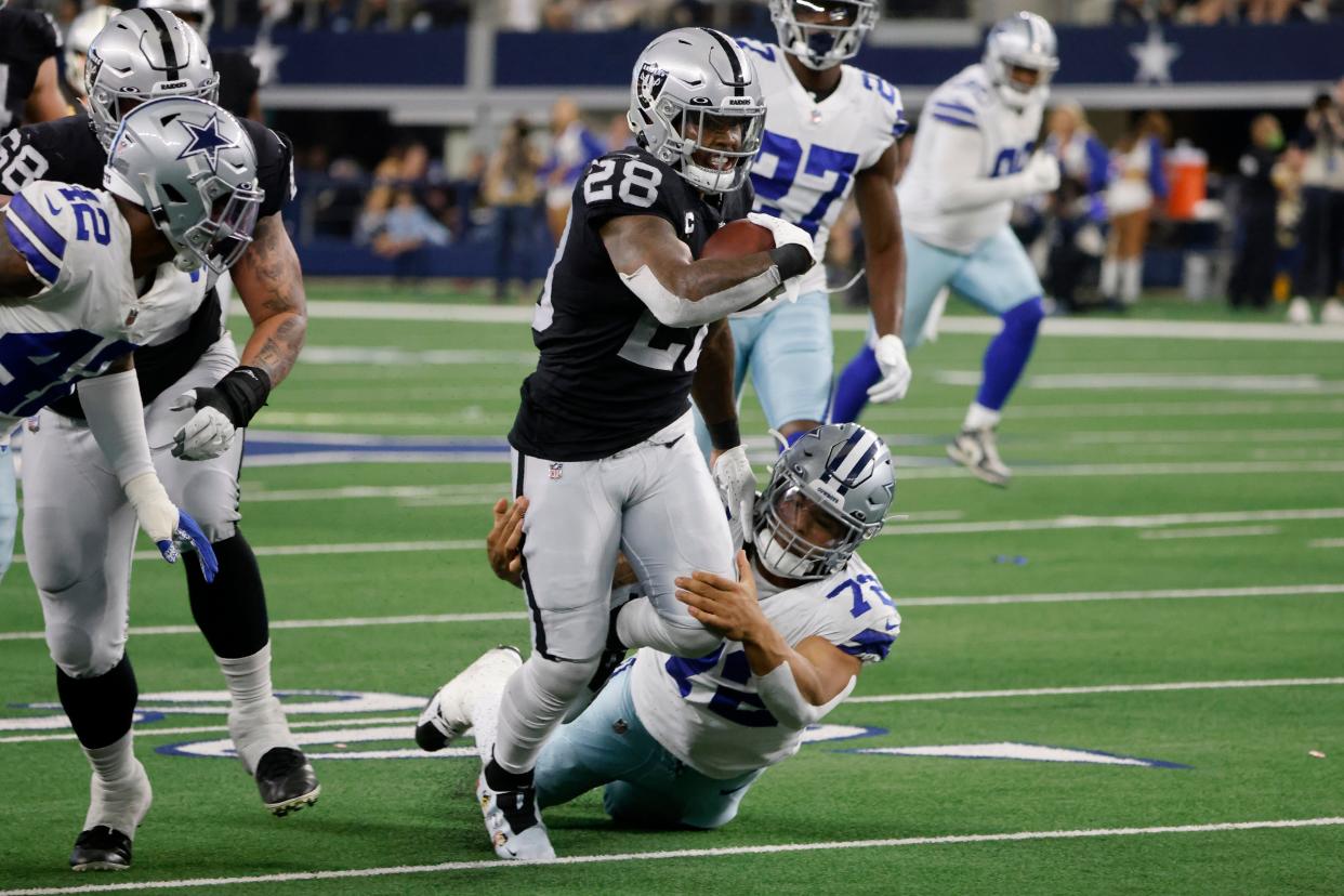 Las Vegas Raiders running back Josh Jacobs (28) picks up a first down as Dallas Cowboys defensive tackle Trysten Hill (72) helps make the stop on Nov. 25, 2021.