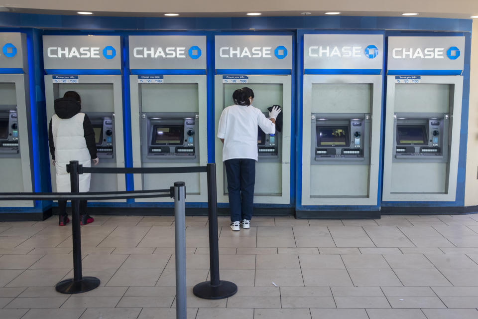 FILE - In this March 24, 2020 file photo, a Chase bank employee, right, cleans the branches ATMs as a customer uses another in the Flushing neighborhood of the Queens borough of New York. Shares of some banks are falling in premarket trading on Friday, March 10, 2023, following SVB Financial Group’s announcement that it plans to raise up to $1.75 billion in order to strengthen its position amid concerns about higher interest rates and the economy. (AP Photo/Mary Altaffer, File)