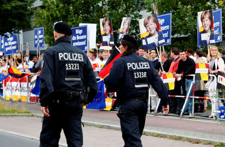 Police walk past supporters of German Chancellor Angela Merkel of the Christian Democratic Union party (CDU) hold banners before a TV debate with her challenger Germany's Social Democratic Party SPD candidate for chancellor Martin Schulz in Berlin, Germany, September 3, 2017. German voters will take to the polls in a general election on September 24. REUTERS/Fabrizio Bensch