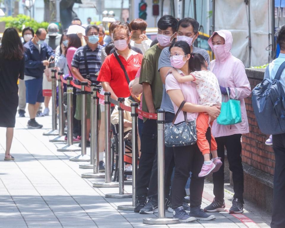 疫情延燒，圖為許多民眾前往篩檢，烈日曝曬下，排隊民眾忍不住皺眉。（粘耿豪攝）