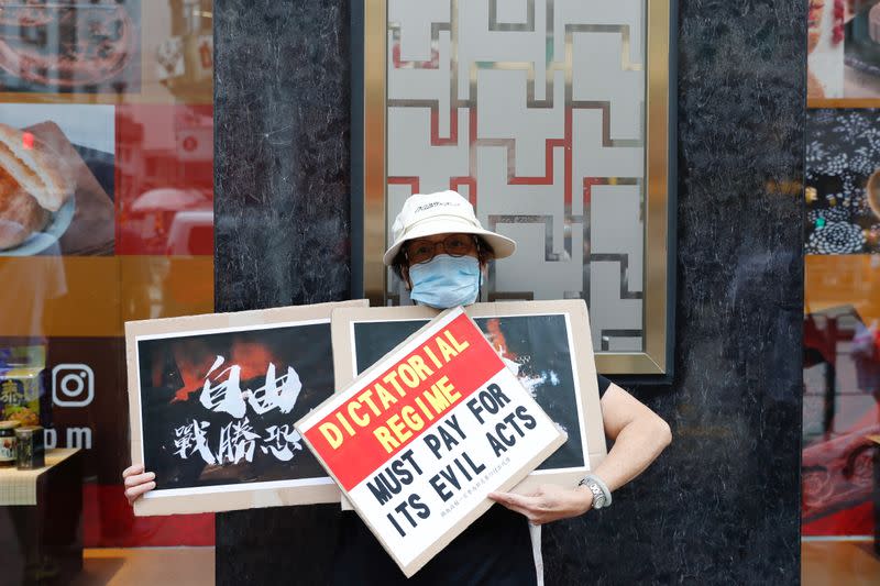 A pro-democracy protester holds placards during a demonstration oppose postponed elections, in Hong Kong