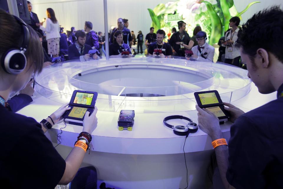 FILE- In this June 11, 2013 file photo, attendees play video games on the Nintendo 3DS at the Nintendo Wii U software showcase during the E3 game show in Los Angeles. The gaming company said Tuesday, May 6, 2014, it wouldn't bow to pressure to allow players to engage in romantic entanglements with characters of the same sex in the English version of "Tomodachi Life" following a social media campaign launched last month seeking virtual equality for the game's characters, which are modeled after real people. (AP Photo/Jae C. Hong, file)