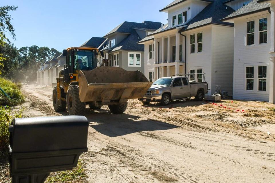 A bulldozer rumbles down the road in front of the Christina and Benji Gecy’s home on Thursday, October. 19, 2023 in the Belleview Bluff subdivision. The 50-foot wide private road known as Roberta Lane is routinely used as part of the construction of Integra Wharf at Battery Creek as it constructs 12, three-story apartment buildings.