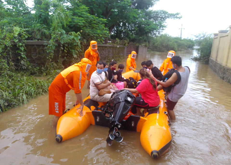 This photograph provided by India's National Disaster Response Force (NDRF) shows NDRF personnel rescuing people stranded in floodwaters in Bhiwandi, in the western Indian state of Maharashtra, Thursday, July 22, 2021. Landslides triggered by heavy monsoon rains hit parts of western India, killing at least five people and leading to the overnight rescue of more than 1,000 other people trapped by floodwaters, an official said Friday. (National Disaster Response Force via AP)