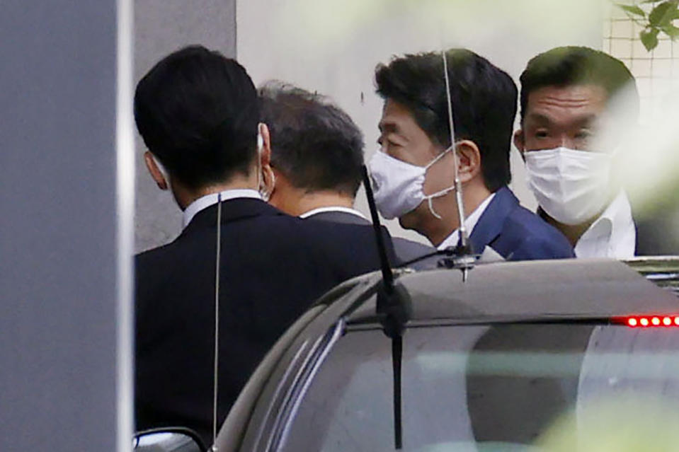 Japanese Prime Minister Shinzo Abe, center right, arrives at Keio University Hospital in Tokyo Monday, Aug. 24, 2020. Prime Minister Abe on Monday became Japan's longest-serving leader in terms of consecutive days in office, but there was little fanfare, as he visited a hospital for another health checkup amid concerns about his health.(Kyodo News via AP)