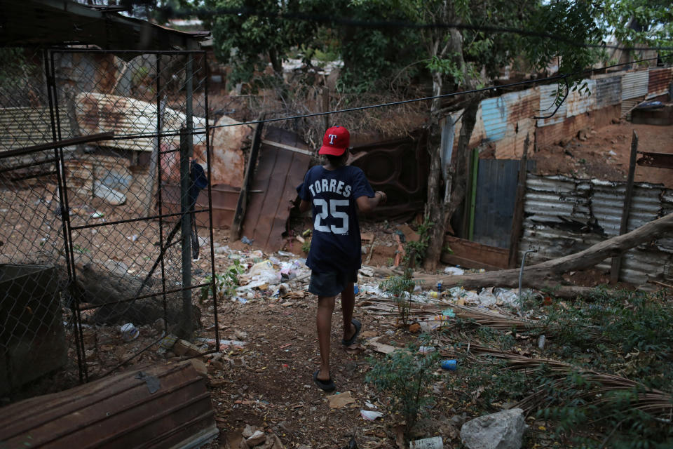 Baseball little league player Adrian Salcedo, 13, walks through his sister's yard in Maracaibo, Venezuela. (Photo: Manaure Quintero/Reuters)