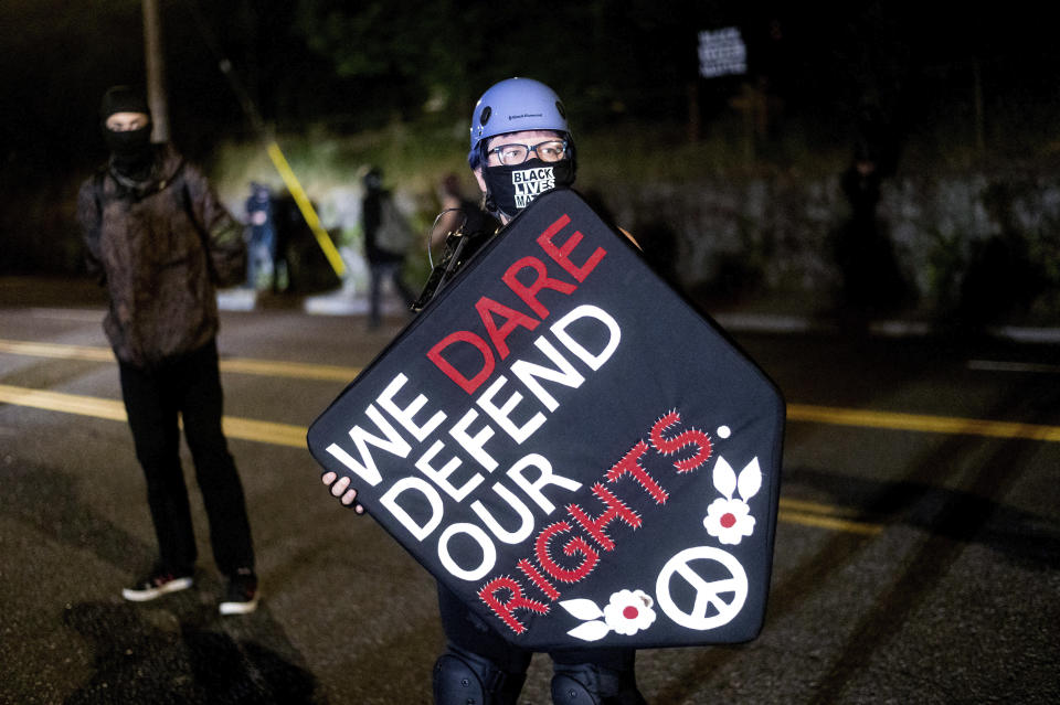 Stacy Kendra Williams sostiene un escudo con el mensaje "Osamos defender nuestros derechos" durante una confrontación con la policía en el Penumbra Kelly Building, el jueves 3 de septiembre de 2020 en Portland, Oregon. (AP Foto/Noah Berger)