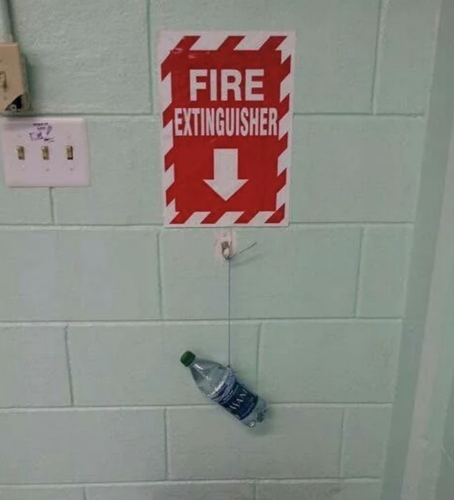 Sign reading "FIRE EXTINGUISHER" with an arrow pointing to a water bottle on a hook