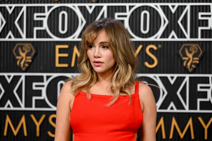Suki Waterhouse wearing a sleeveless dress poses in front of a FOX backdrop at an Emmy-related event