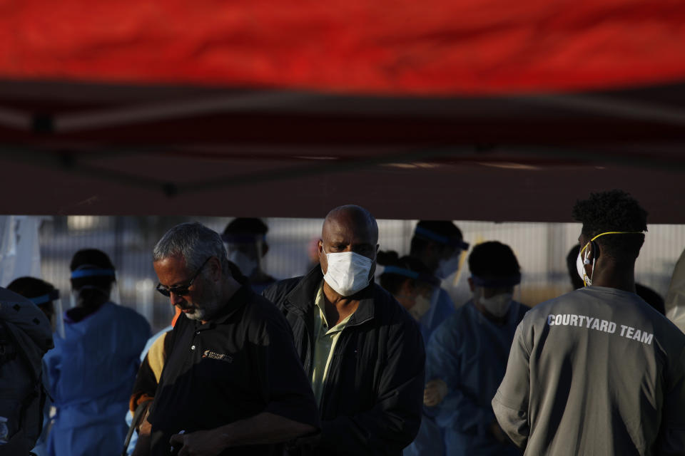 People wait in line to enter a makeshift camp for the homeless Monday, March 30, 2020, in Las Vegas. Officials opened part of a parking lot for the camp after a local shelter closed when a man staying there tested positive for the coronavirus. (AP Photo/John Locher)