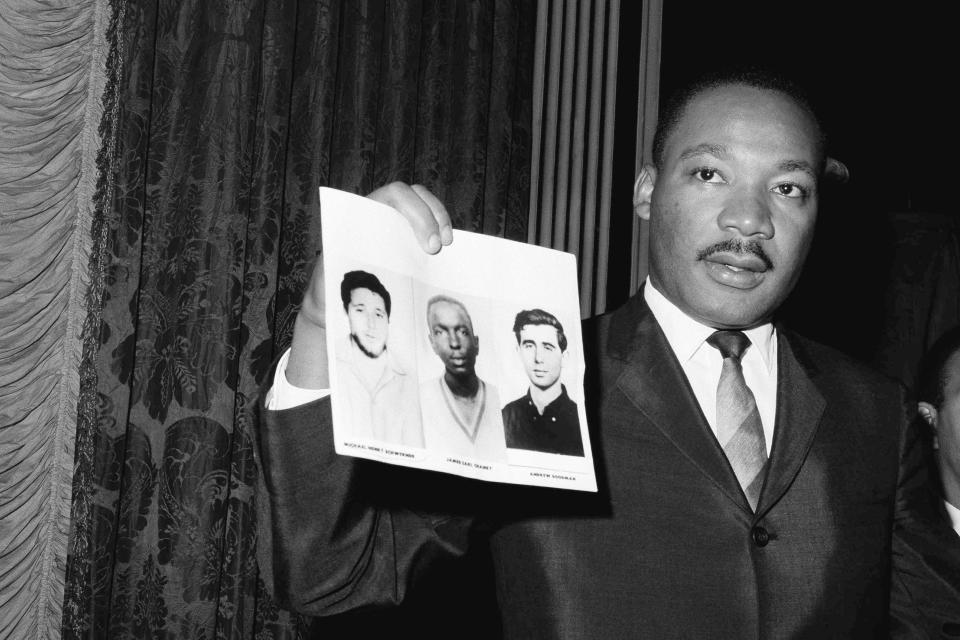 Civil Rights leader Martin Luther King, Jr., displays pictures of three civil rights workers at news conference on Dec. 4, 1964, in New York City. Stephen Schwerner doesn't remember how he learned that his younger brother Michael, nicknamed Mickey, was missing in Mississippi along with colleagues Andrew Goodman and James Chaney. What he remembers is that as soon as the family heard the news, they were certain of their fate: "We were sure they were killed," he says. It was the summer of 1964, an era marked by murders, beatings, disappearances and church bombings amid the struggle for voting rights and the fight against segregation. (AP Photo/ John Lindsay)