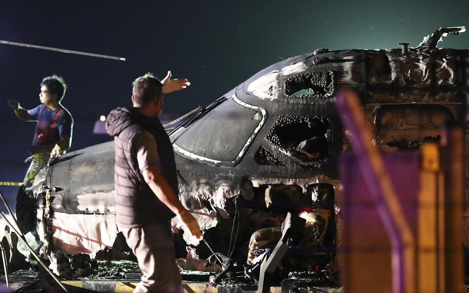 An airport personnel walks beside the remains of a Lion Air, West Wind 24 aircraft after it caught fire during take off at Manila's International Airport in Philippines on Sunday, March 29, 2020. A plane carrying eight people has caught fire while attempting to take off from Manila's airport on a flight bound for Japan, killing all those on board, officials said. (AP Photo)