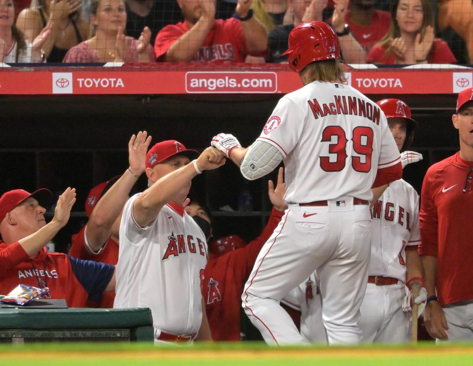 Los Angeles Angels first baseman David MacKinnon (39) is congratulated in the dugout by interim manager Phil Nevin (88) after hitting a sacrifice fly to score a run in the fifth inning of the game against the Kansas City Royals at Angel Stadium on June 22, 2022.