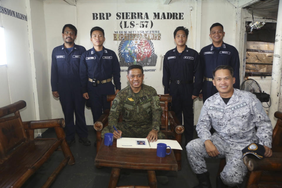 In this handout photo provided by the Armed Forces of the Philippines PAO, Philippine military chief, General Brawner, center seated, and Vice Admiral Alberto Carlos, right, Commander of the AFP's Western Command poses for pictures during their visit with Filipino marines and navy personnel stationed aboard the long-marooned BRP Sierra Madre at the Second Thomas Shoal, locally known as Ayungin Shoal, at the disputed South China Sea on Sunday Dec. 10, 2023. The Philippine military chief said Monday he was with Filipino forces aboard a supply boat when it was blasted with a water cannon and surrounded and bumped by Chinese coast guard ships over the weekend in the disputed South China Sea. (Armed Forces of the Philippines PAO via AP)