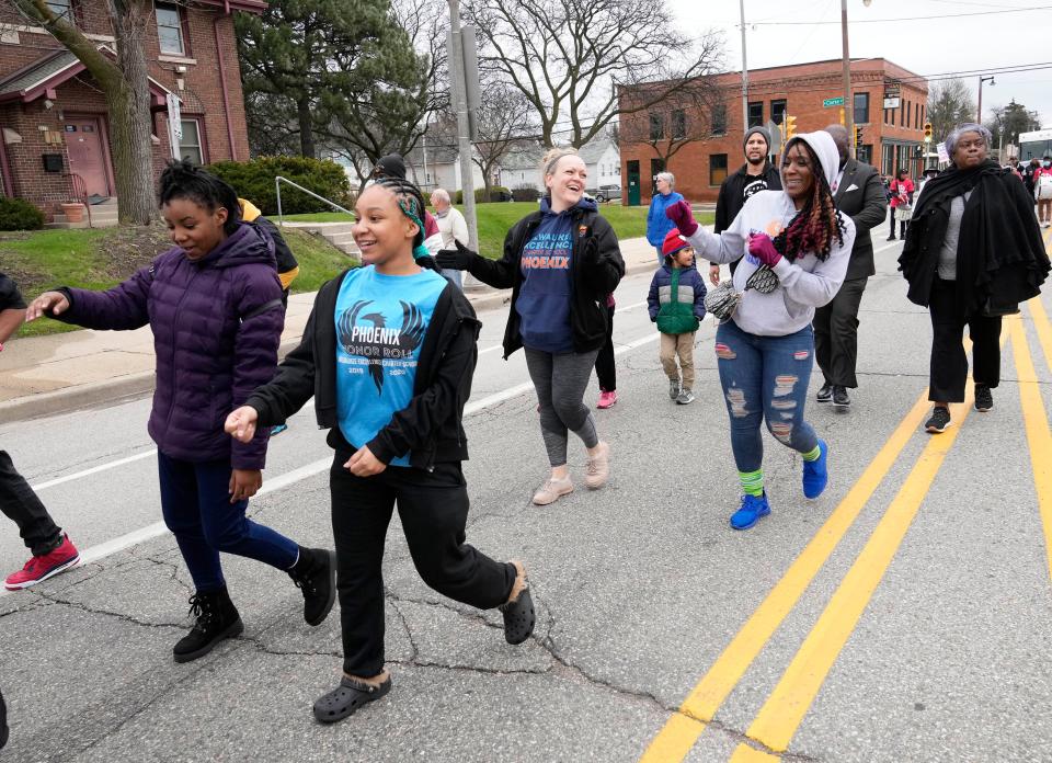 Nadia Ellis, left, a 12-year-old sixth grader, and her sister, Rena Ellis, a 15-year-old freshman, both attending Milwaukee Excellence Charter School, walk with their mother, Mercedes Ferguson, second right, and Lyndee Belanger, center, senior director of talent at Milwaukee Excellence, during the Youth Victory Over Violence Walk along North King Drive in Milwaukee on Sunday.