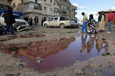 People walk near a puddle of water mixed with blood at the site of twin car bombs in Benghazi, Libya, January 24, 2018. REUTERS/Esam Omran Al-Fetori