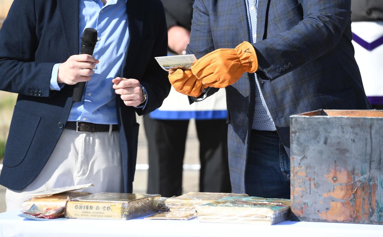 Mayor Jerome Rice, right, takes items out of a time capsule that was embedded in a cornerstone of the former Spartanburg City Hall. The time capsule was unsealed during a ceremony Wednesday, April 3, 2024.