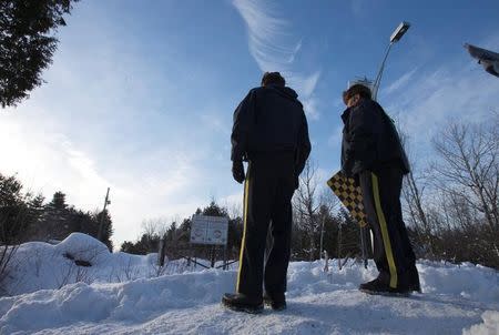 Royal Canadian Mounted Police (RCMP) officers stand on a hill looking over the U.S.-Canada border into Hemmingford, Quebec, Canada February 14, 2017. REUTERS/Christinne Muschi/Files