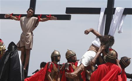Penitent Ruben Enaje (R), in his 28th year of crucifixion, is lowered from a wooden cross after re-enacting the death of Jesus Christ on Good Friday in San Fernando, Pampanga in northern Philippines April 18, 2014. REUTERS/Erik De Castro