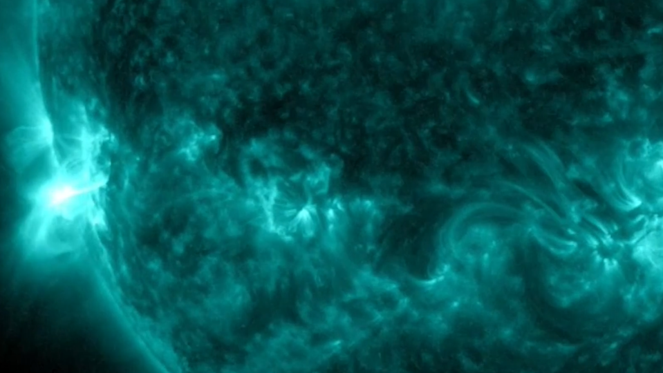 a close-up of the sun in false color wavelengths, with a burst of flare on the left limb