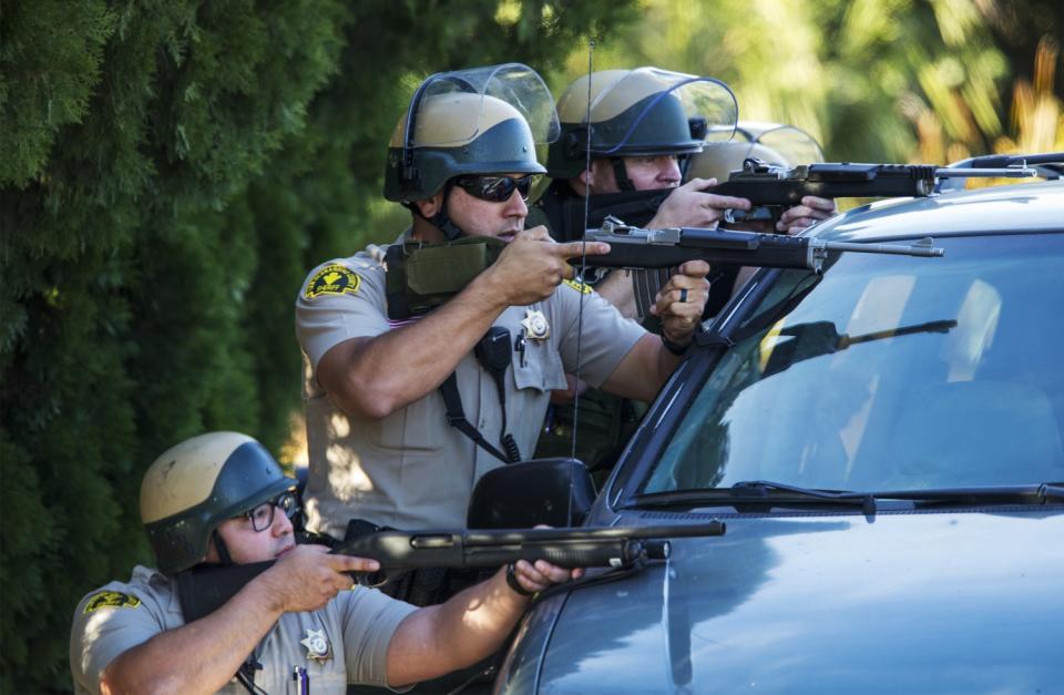 Sheriff's deputies behind a van with guns drawn