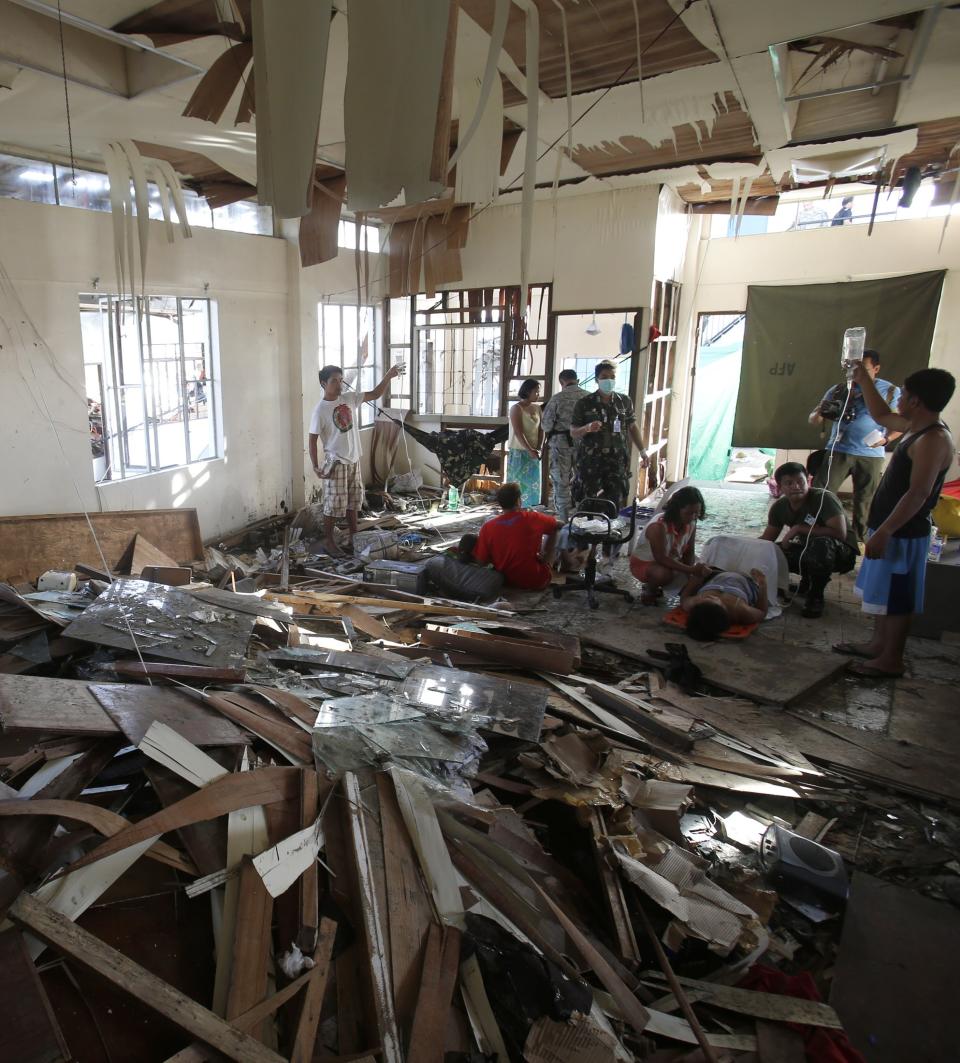 A pregnant woman and a mother who has just given birth lie inside a room that was damaged at the height of super Typhoon Haiyan in Tacloban city