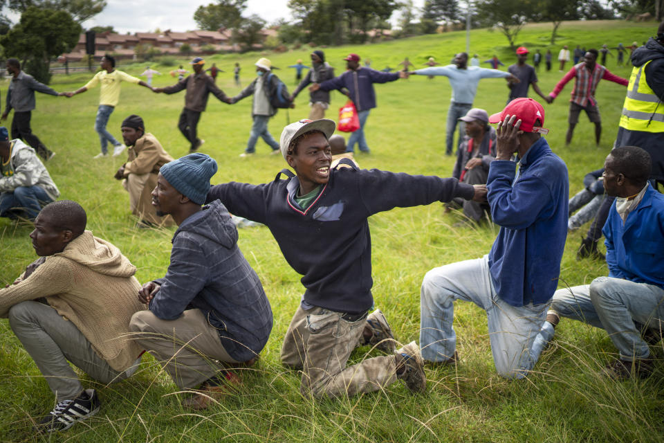 Homeless recyclers and other destitute people, some of whom said they have not eaten in three days, are asked to practice social distancing by police as they lineup in a Johannesburg park, waiting to receive food baskets from private donors, Thursday, April 9, 2020. Because of South Africa's imposed lockdown to contain the spread of COVID-19, many people who don't have savings and are unable to work are not able to buy food. (AP Photo/Jerome Delay)